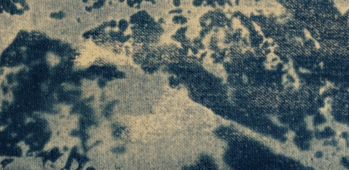 A close-up of a texture fabric with a dark navy blue and beige pattern. Cyanotype